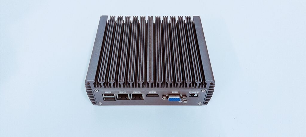 Angled view of a fanless industrial mini PC showing the finned aluminum chassis